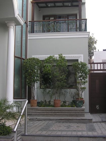 This home features an asymmetrical entrance that is centered yet unconventional. A recessed foyer with a warm solid wood door opens into a long, open corridor, establishing a journey through the space.
