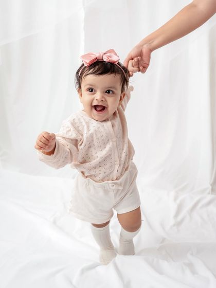 A baby girl taking her first steps with a little help.