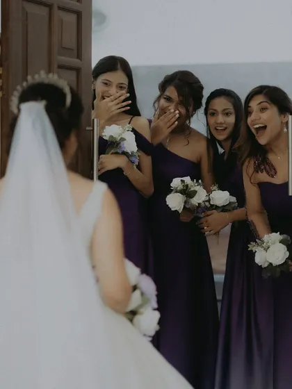 The priceless reaction of the bridesmaids seeing the bride in her wedding gown for the first time.