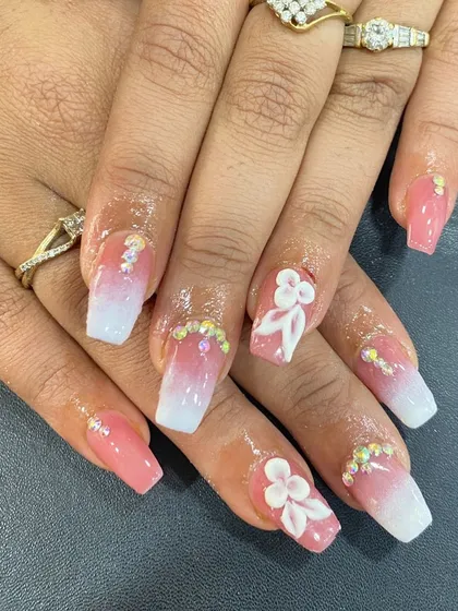 A soft pink and white ombre set on square nails, adorned with 3D flowers and iridescent rhinestones.