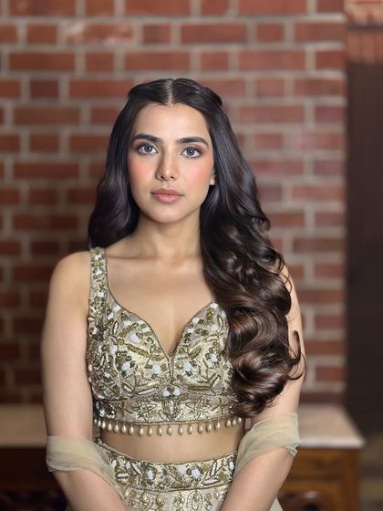 A simple yet beautiful half-up style with a center part and twisted sections pinned back. The rest of the hair is styled in large, bouncy curls for a soft, romantic feel.