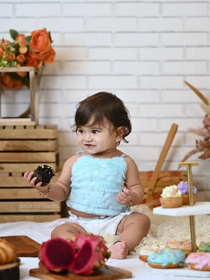 A candid shot of a baby girl enjoying a treat during her studio photoshoot.