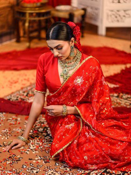 A seated pose showing the full grace of the traditional red saree look I created for my students.