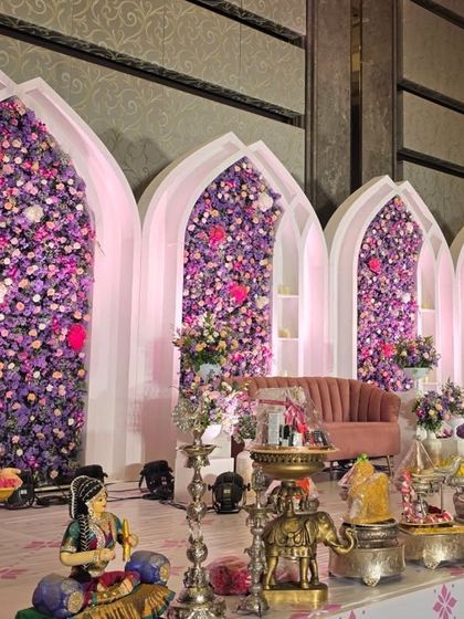 A grand stage featuring five large white arches filled with a dense arrangement of purple and pink flowers. This design creates a sense of depth and grandeur.