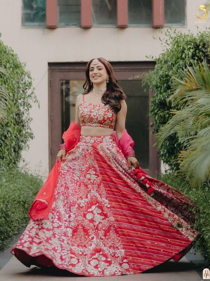 The full twirl-worthy effect of the open hairstyle with her gorgeous red lehenga.