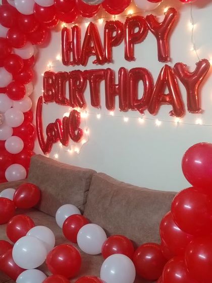 A red, white, and silver balloon arch and wall decoration for a home party.