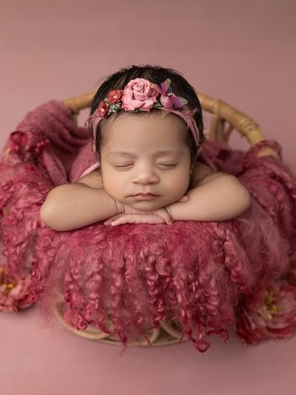 A wider view of the pink basket setup, showing the beautiful arrangement of the fabric and flowers that create a soft bed for the baby.