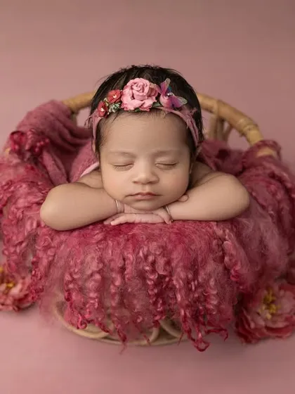 A wider view of the pink basket setup, showing the beautiful arrangement of the fabric and flowers that create a soft bed for the baby.