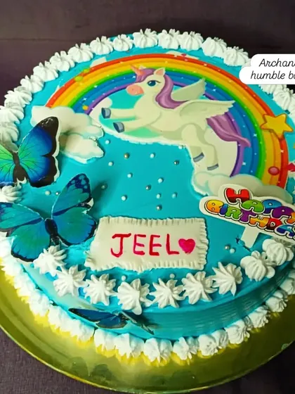 A simple and sweet unicorn cake with a rainbow and butterfly accents.