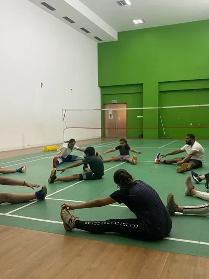 Every session begins with proper preparation. Our players, a mix of kids and adults, focus on flexibility with group stretching to prevent injuries and improve their reach on the court.