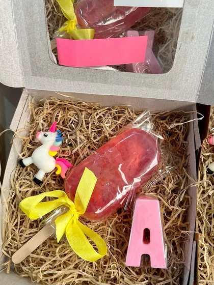 A look inside the popsicle gift box, showing the soap, initial, and unicorn keychain nestled in kraft paper.