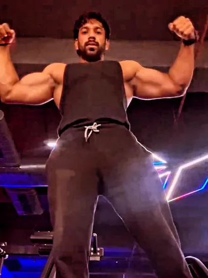 A powerful front double biceps pose from a low angle, emphasizing size and dominance. Posing is about creating an illusion of being larger than life.