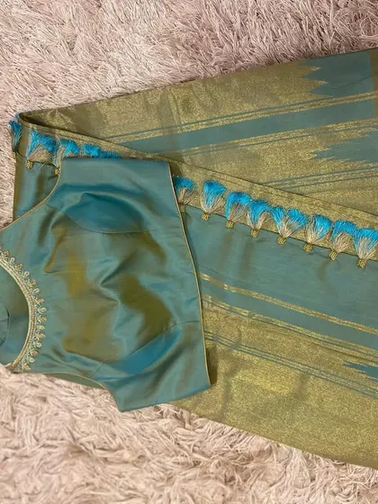The front of the teal silk blouse, showing its sleeveless design and elegant, minimalist embroidery.