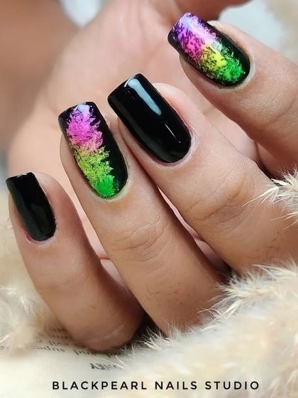 A closer look at the black nails with colorful pigment art, showing the beautiful blend of neon colors against the dark base.