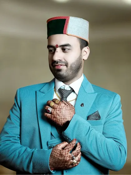 A stylish pose showing the groom's full attire. The focus on his hands, adorned with rings and henna, adds a layer of detail to the portrait.