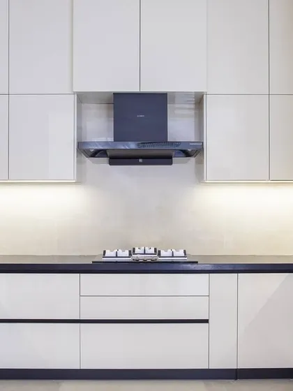 A minimalist modular kitchen where form meets function. White high-gloss cabinets open up the space, while black metallic accents and warm under-cabinet lighting add a refined edge.