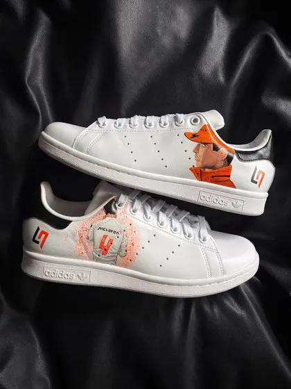 A pair of crisp white Adidas Stan Smiths customized with a detailed portrait of McLaren F1 driver Lando Norris and his car number.