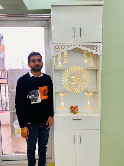 Presenting a finished pooja unit in a high-gloss white finish. The backlit jali panel with the "Om" symbol creates a serene ambiance.