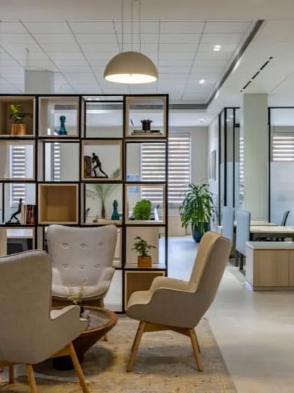 The open-backed shelving unit in this lounge acts as a functional piece of art, dividing the space while allowing light to pass through and providing surfaces for decorative objects.