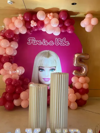 The main stage for the "Five is a Vibe" Barbie party, showing the custom backdrop, balloon garland, and fluted plinths for the cake.