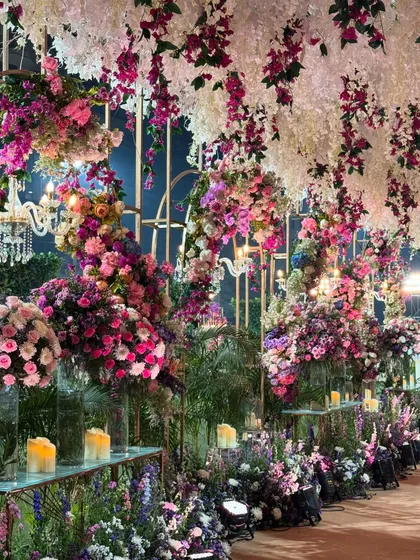 A closer look at the melange of florals. This walkway is lined with candles and an abundance of flowers in shades of purple and pink, creating an immersive and romantic path.
