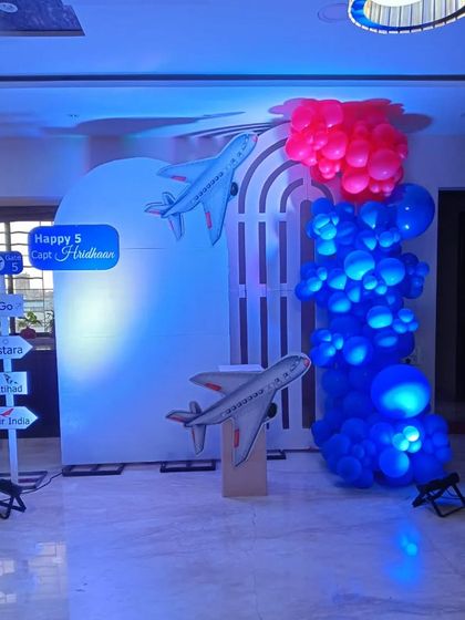 An airplane-themed party for 'Captain Hridhaan'. This setup features a white arched backdrop with airplane cutouts and a directional sign pointing to different airlines.