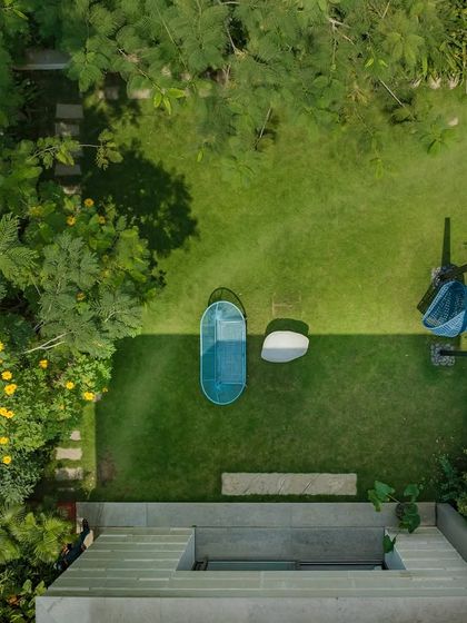 An aerial view of a garden designed with distinct zones for relaxation. The layout includes a sunken seating area and a separate spot with a swing, all connected by pathways and surrounded by lush greenery.
