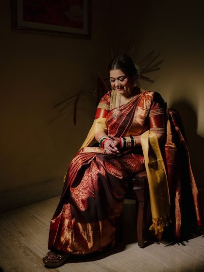 A quiet, contemplative moment captured as the bride looks down, her hands clasped. The dramatic lighting adds a touch of artistry.