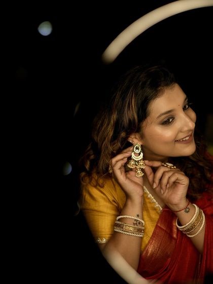 A playful shot highlighting the beautiful jhumka earrings against a dark background.
