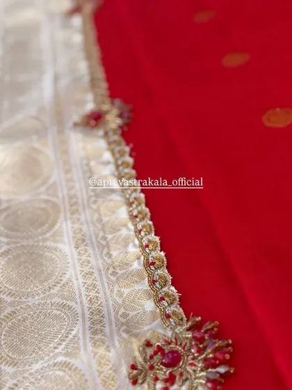 An elegant border featuring red stone floral motifs, placed between a white brocade and a plain red silk fabric.