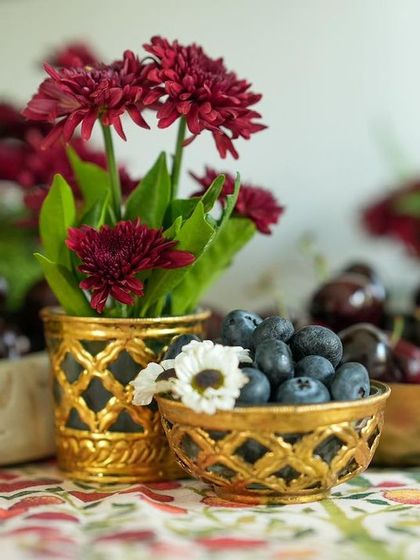 A close-up of the small brass bowls filled with blueberries and flowers, part of the intricate tablescape.