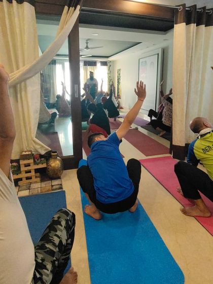 Students practice a squat variation with a twist in our Delhi studio. The mirror reflects the energy of the full class, showing a vibrant and active community.