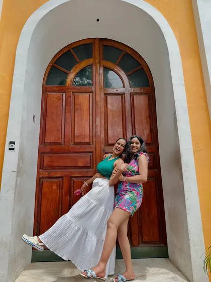Two friends having fun and posing in front of a classic colorful door in Pondicherry's French Quarter.