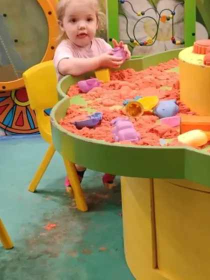 A young child focuses on creating shapes and structures at our popular kinetic sand table.