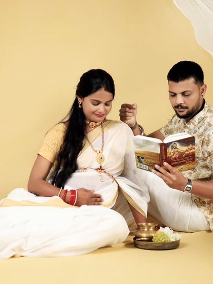 The couple is captured reading together in their beautiful white and gold South Indian outfits. This studio setup is designed to be peaceful and culturally significant.