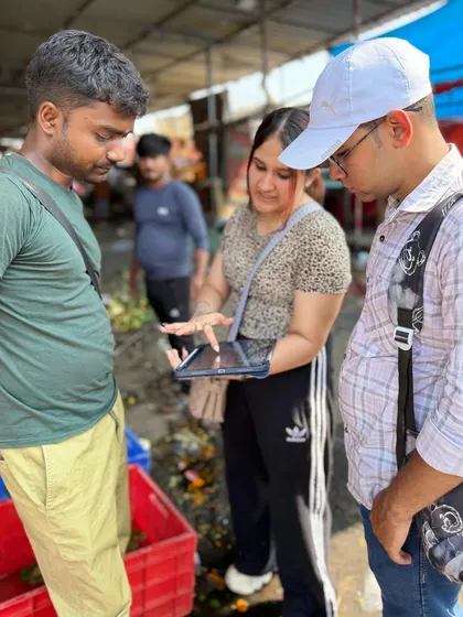 Students use a tablet to coordinate plans and pricing with a vendor at the flower market, applying their classroom knowledge to a real-world scenario.