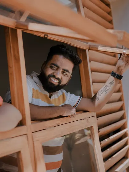 A happy, candid shot of the groom-to-be looking out a wooden window, full of anticipation.