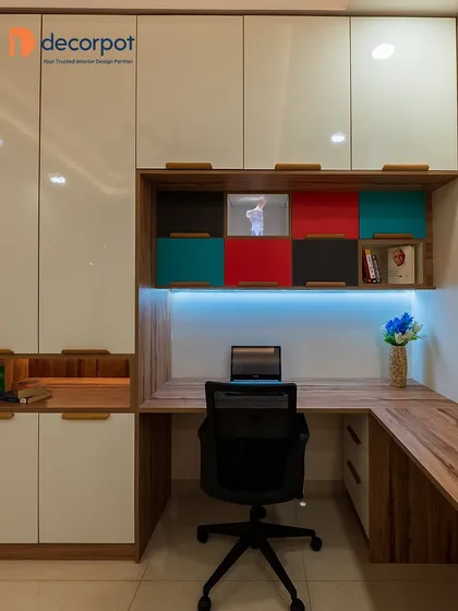 A productive workspace starts with smart design. This L-shaped study table is integrated with ample overhead and side storage, featuring a mix of closed cabinets and colorful open shelves for a personalized and organized home office.