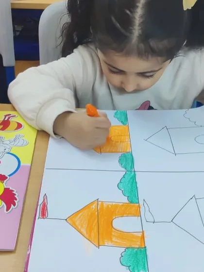 A young girl carefully colors in her drawing of a house. We use simple outlines to help beginners get started with confidence.