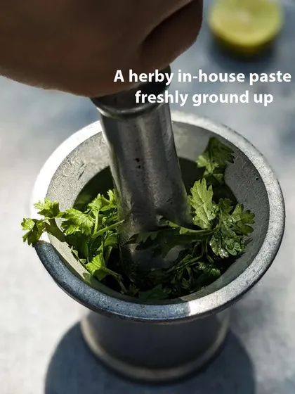 Grinding our coriander pesto by hand in a mortar and pestle. This traditional method helps release the essential oils and flavours of the fresh herbs.