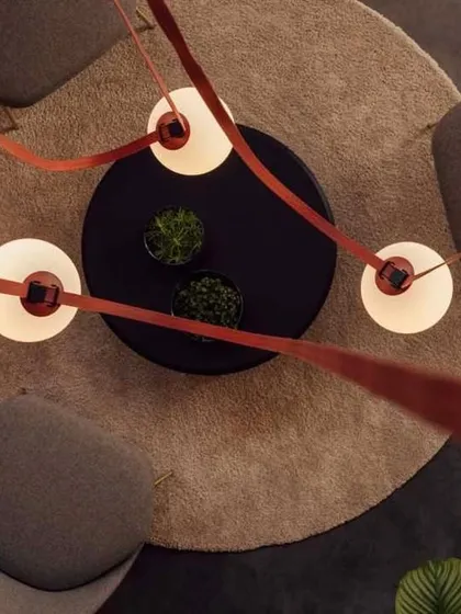 A top-down view of our Braided Tape Series installed over a seating area. The red tapes create a vibrant, graphic pattern against the ceiling, with the spherical lights providing focused illumination for the space below.