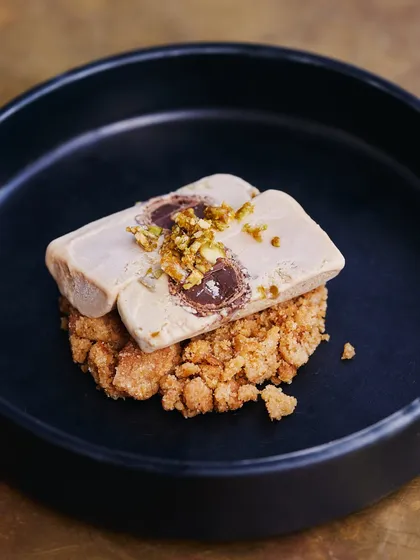 Our Salted Chikki Kulfi is a playful and inventive dessert. The traditional Indian ice cream is paired with the salty crunch of peanut brittle, creating a delightful contrast of textures and flavors.