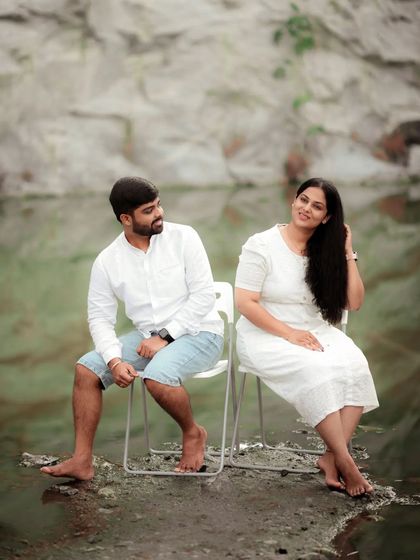 A serene and artistic pre-wedding shot of a couple sitting by the water, their reflection creating a beautiful visual.
