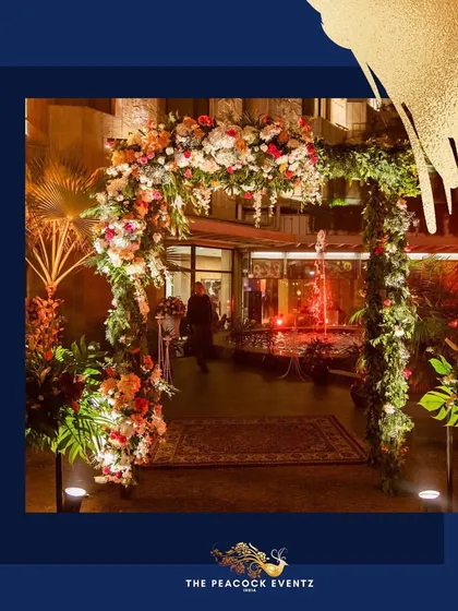 This floral archway, crafted with a mix of colorful flowers and fresh greenery, served as a beautiful entrance for a cocktail event. The warm lighting highlights the intricate arrangement, creating an inviting and luxurious feel.