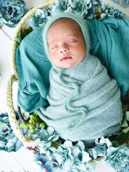 An artistic angle of the baby in the basket, surrounded by blue flowers, showcasing the full setup.