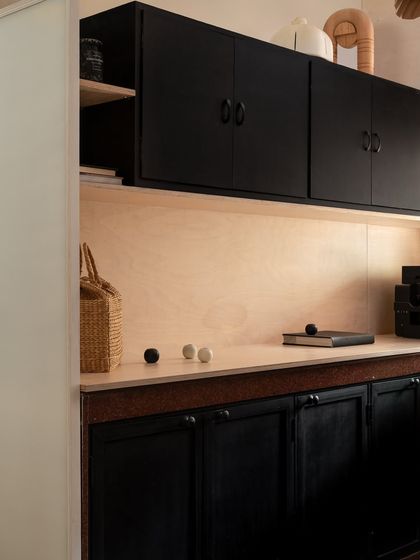This is our material pantry and storage area, where we keep samples and project essentials organized. We used simple, clean lines with black cabinetry and a light wood backsplash to create a functional zone that remains consistent with the studio's overall aesthetic.