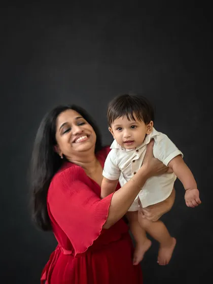 A mother's joy is so evident as she lifts her baby up. The dark background makes their expressions and connection the sole focus of the image.