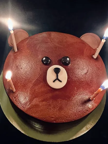 A simple but adorable bear face cake, lit with birthday candles.
