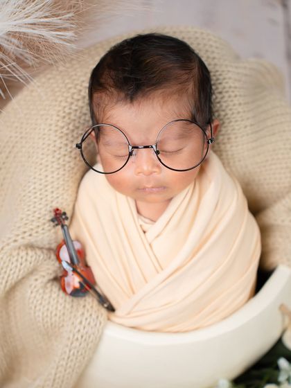 For the family of book lovers or musicians. This creative newborn portrait features a sleeping baby with tiny glasses and a miniature violin, showing how we can personalize your session.