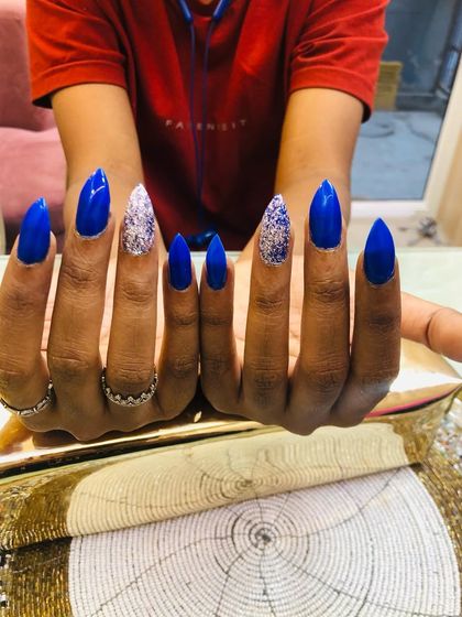 The stiletto shape of these nails adds to the drama of the blue and silver glitter combination.